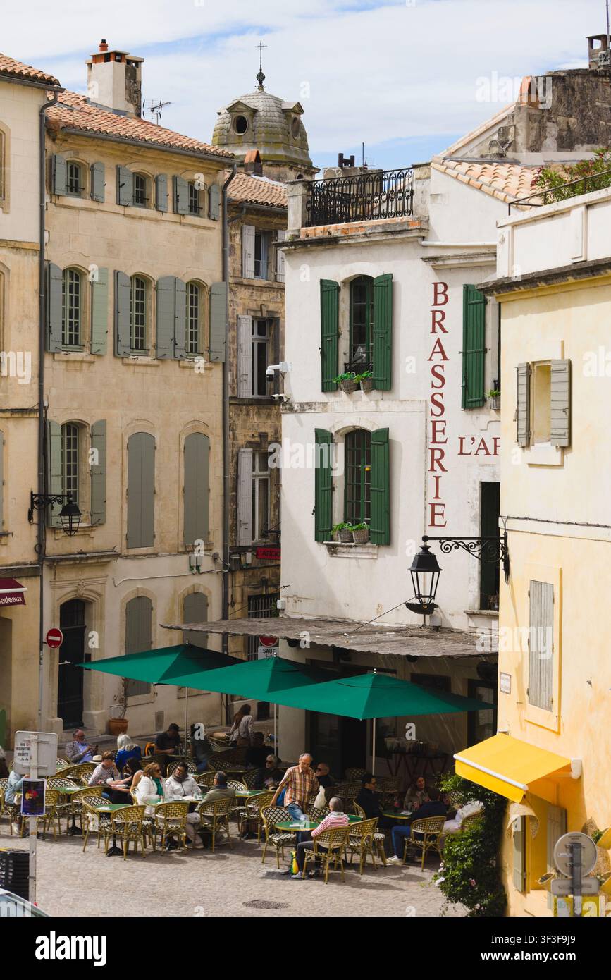 Vue élevée des clients assis aux tables de la terrasse extérieure d'un restaurant brasserie sur une place animée à Arles, France. Banque D'Images