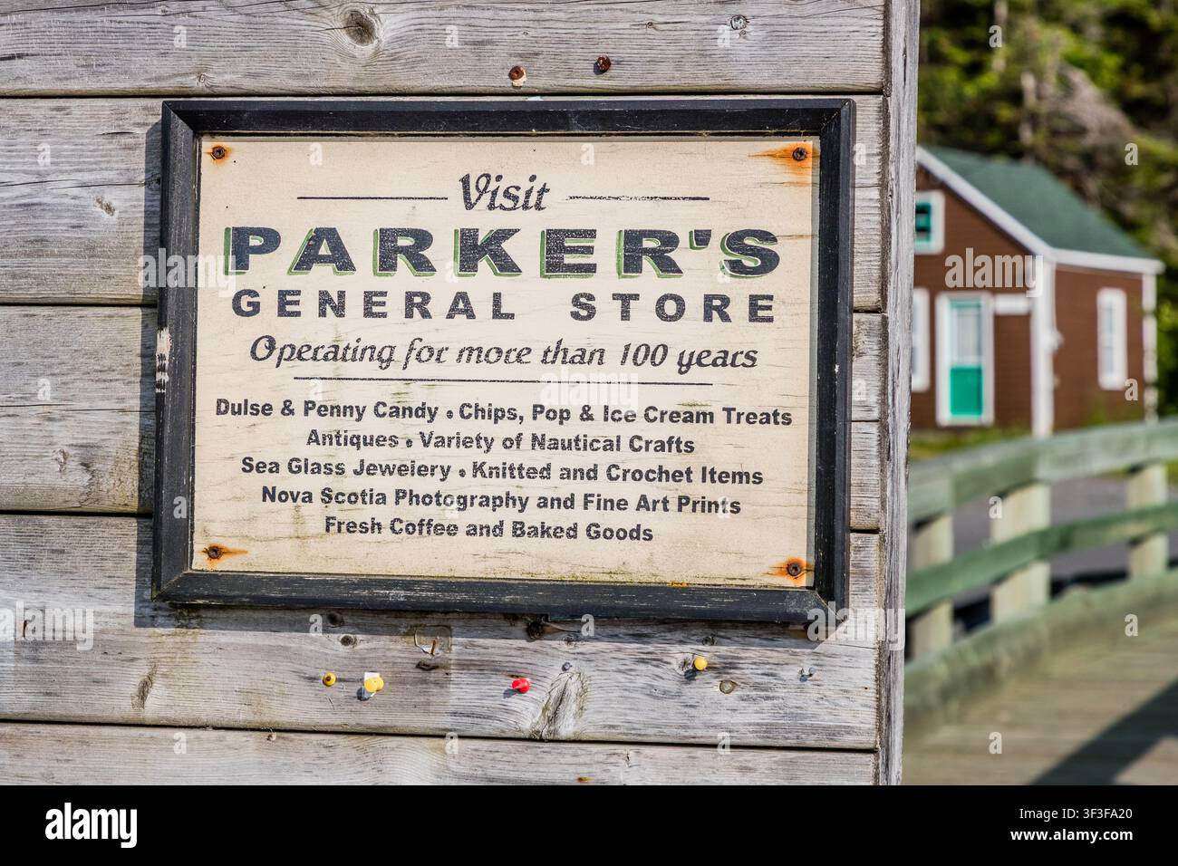 Une enseigne en bois historique fait la promotion de Parker’s General Store à Halls Harbour, en Nouvelle-Écosse, au Canada. La famille Parker gère l’épicerie générale, fondée en 1905, depuis plus de 100 ans, vendant des articles tels que du goémon, des sucreries, de l’artisanat et du café Banque D'Images