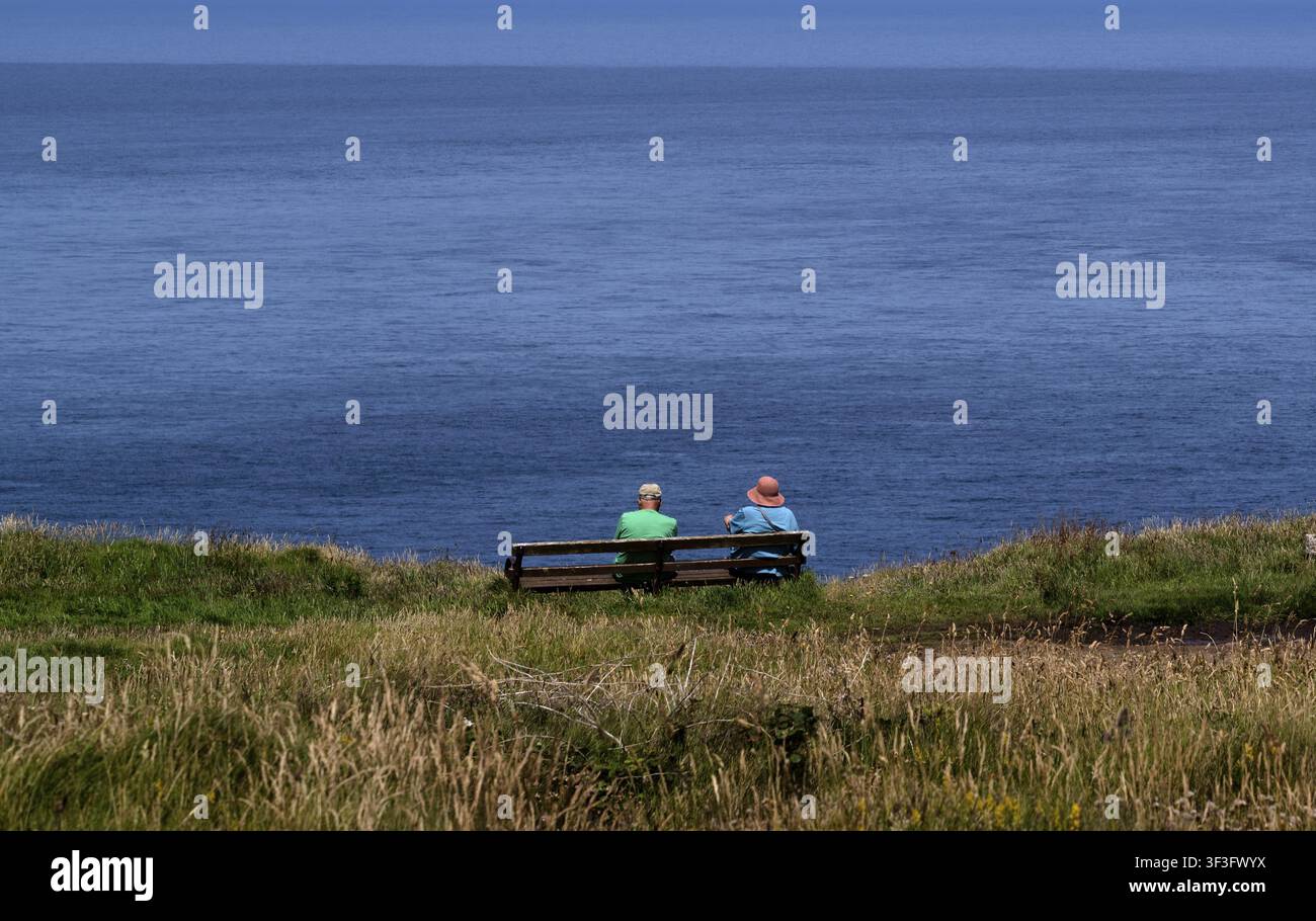 Couple âgé, homme, femme, assis sur un banc en train de regarder la mer, côte, St Just in Penwith, Cornouailles, Angleterre, Grande-Bretagne, Grande-Bretagne Banque D'Images