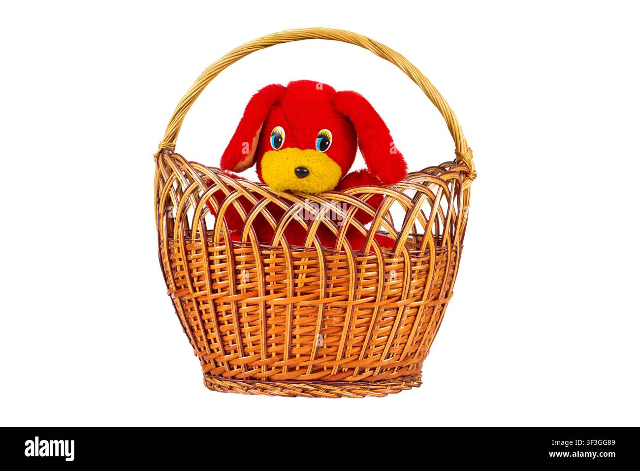 Un chien jouet dans un panier sur fond blanc. Jouet doux dans un panier en osier. Banque D'Images