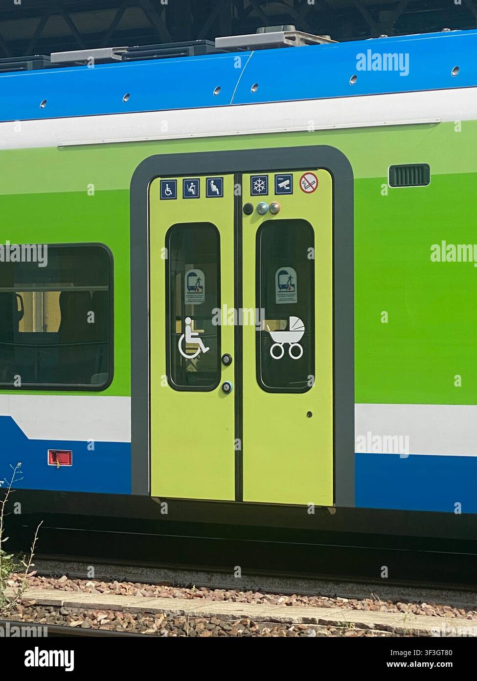 Cremona, Italie – 2 juin 2026 Vue rapprochée de la carrosserie d’un train montrant des portes vert vif avec des symboles d’accessibilité universelle et de poussette indiquant Banque D'Images