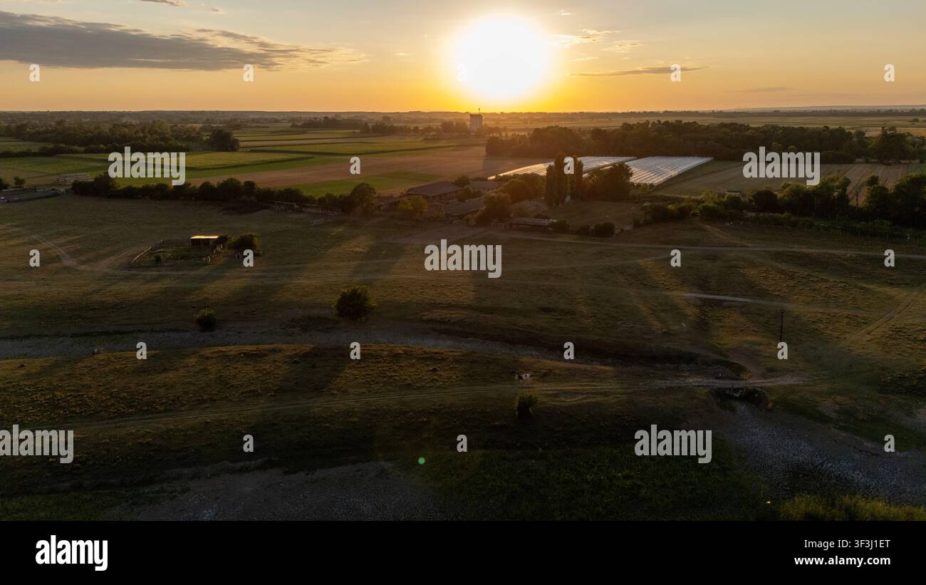 Vue aérienne de la réserve naturelle spéciale Zasavica au coucher du soleil, mettant en scène des champs agricoles, des serres et un paysage rural à Zasavica, Vojvodina, Serbie Banque D'Images