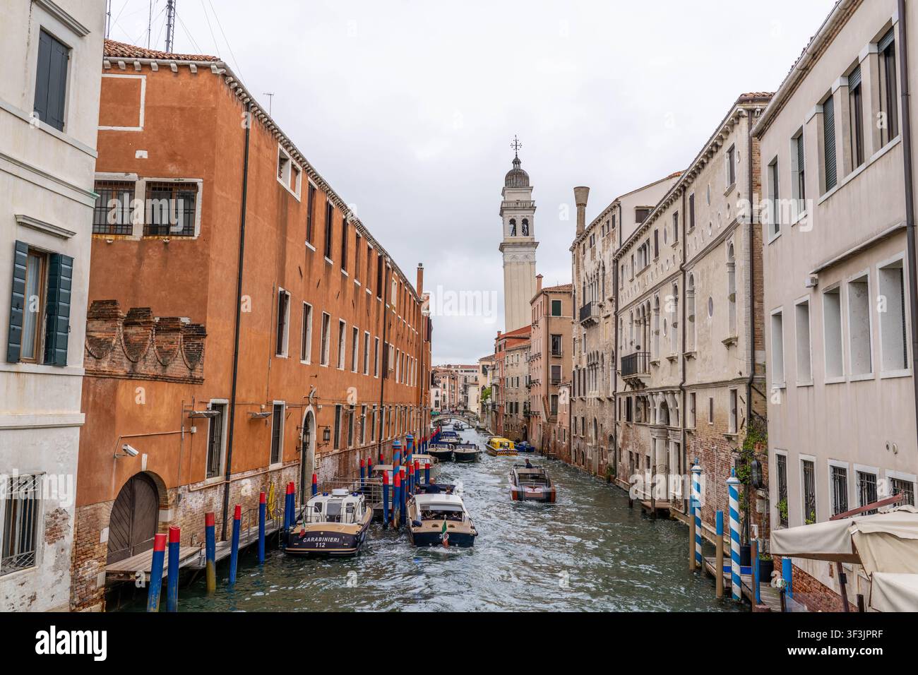 Venise Italie - 2 septembre 2025 : Un canal étroit avec des bateaux et des bâtiments historiques par une journée nuageuse à Venise Italie Banque D'Images