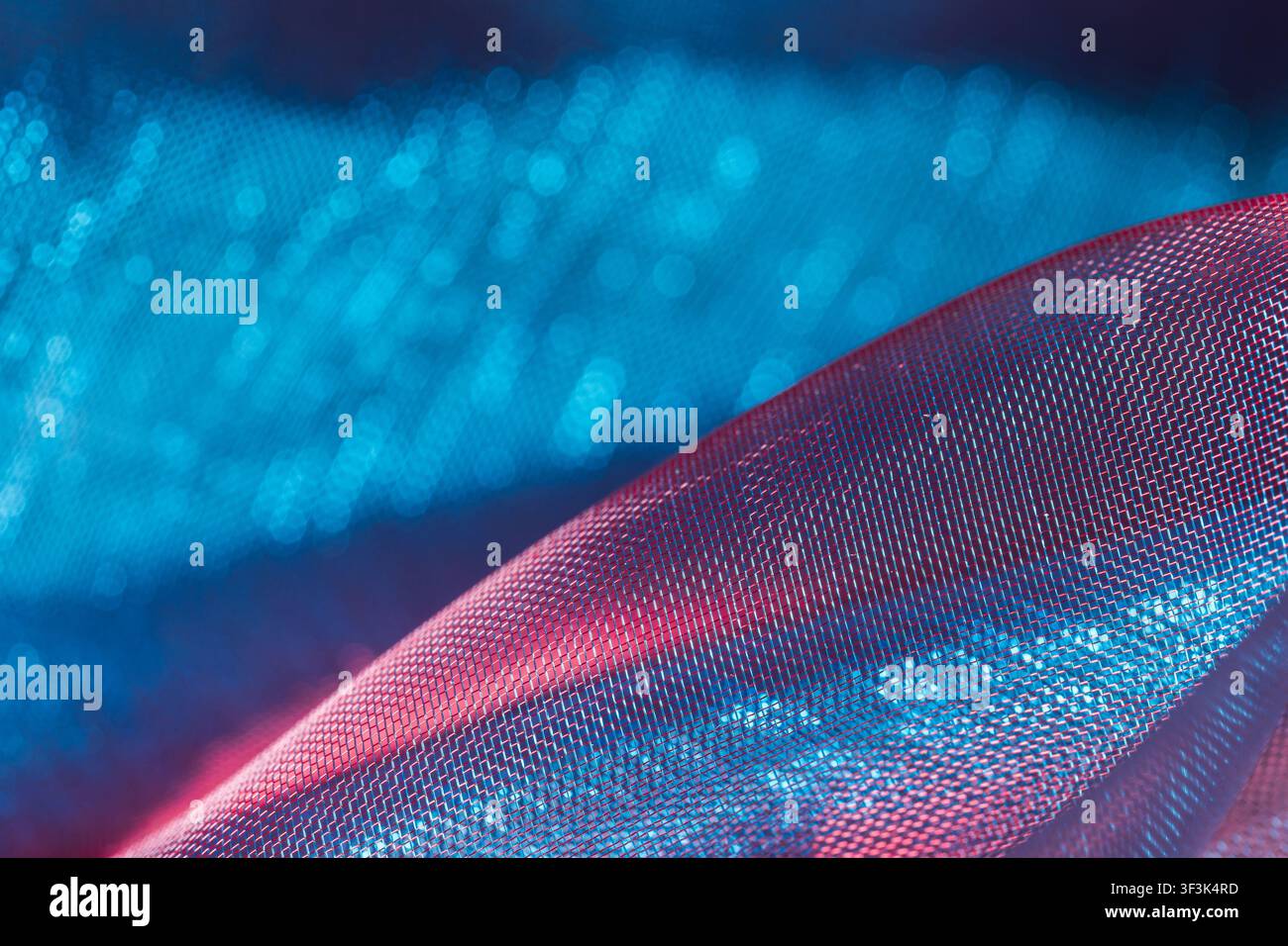 Grossissement d'un tissu filet translucide avec des tons bleus et rouges vibrants, mise au point douce et bokeh Banque D'Images