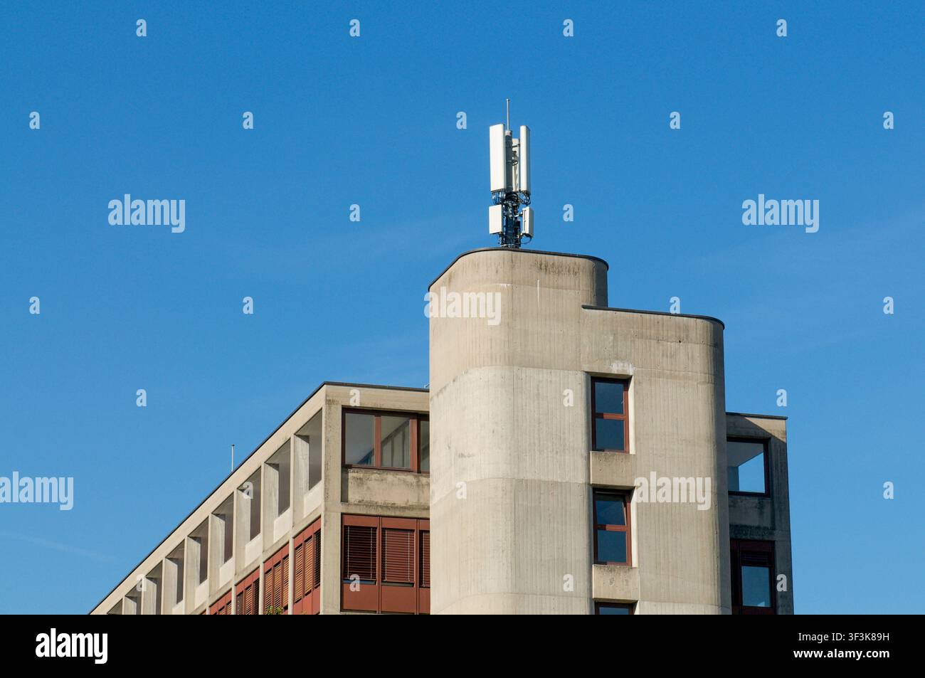 Antennes de station de base de téléphone mobile montées sur le toit d'un bâtiment moderne en béton dans le Tessin. Vue en contre-plongée du pylône de téléphonie cellulaire Banque D'Images