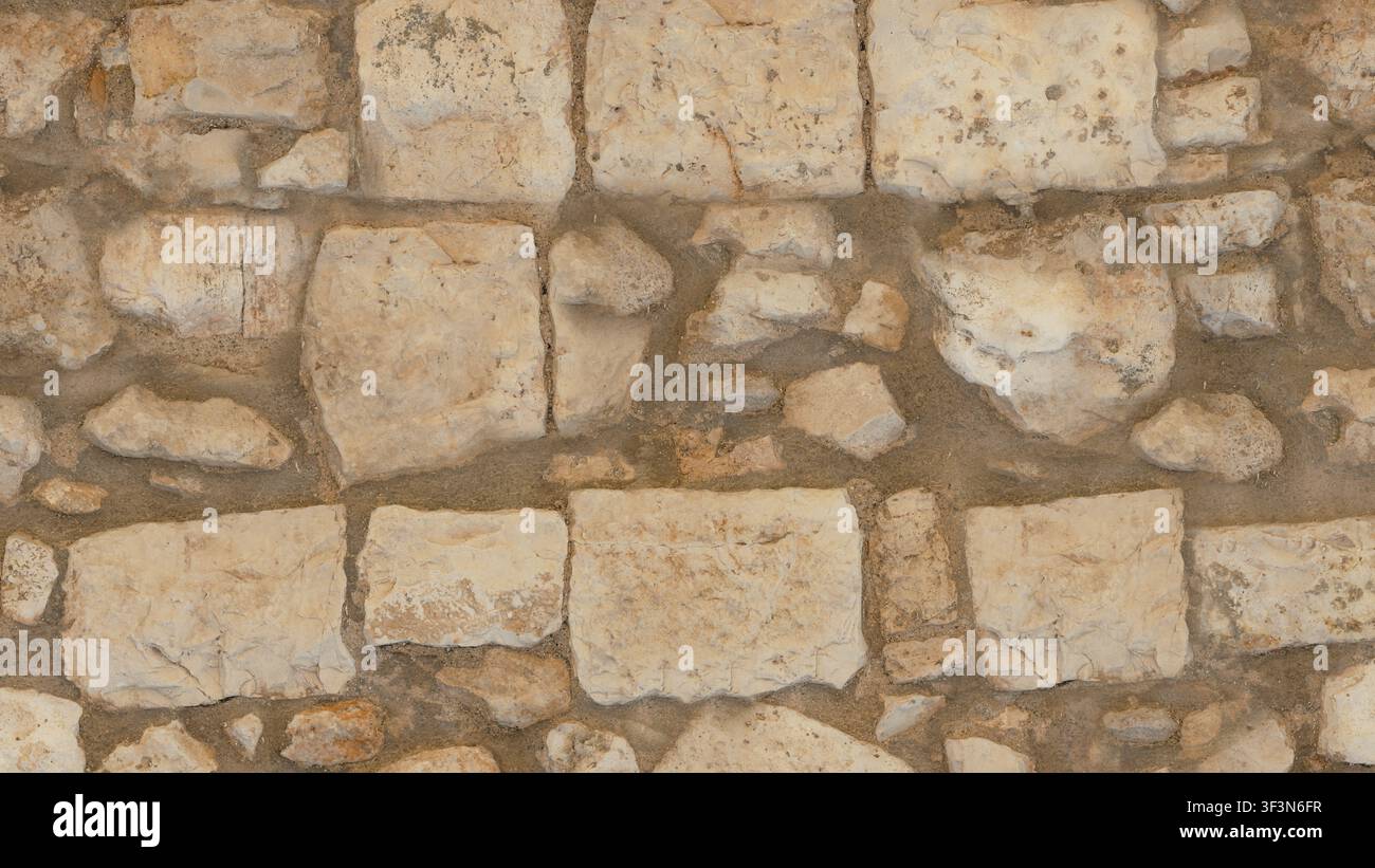 Une texture en gros plan d'un mur ancien construit à partir de blocs de calcaire taillés à la main, de couleur claire, assemblés avec du mortier. Banque D'Images