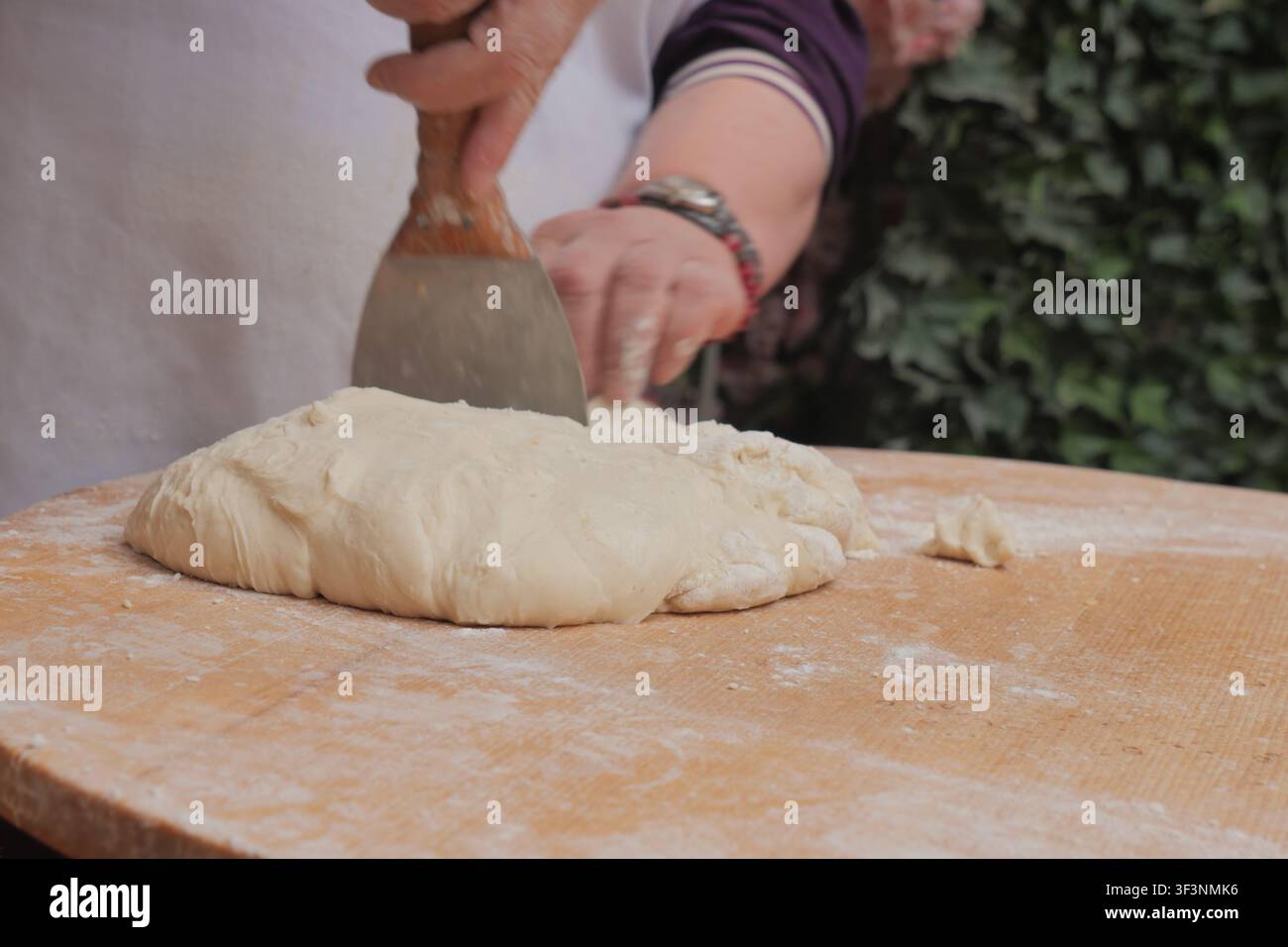 Une personne prépare de la pâte sur une surface en bois dans la cuisine Banque D'Images