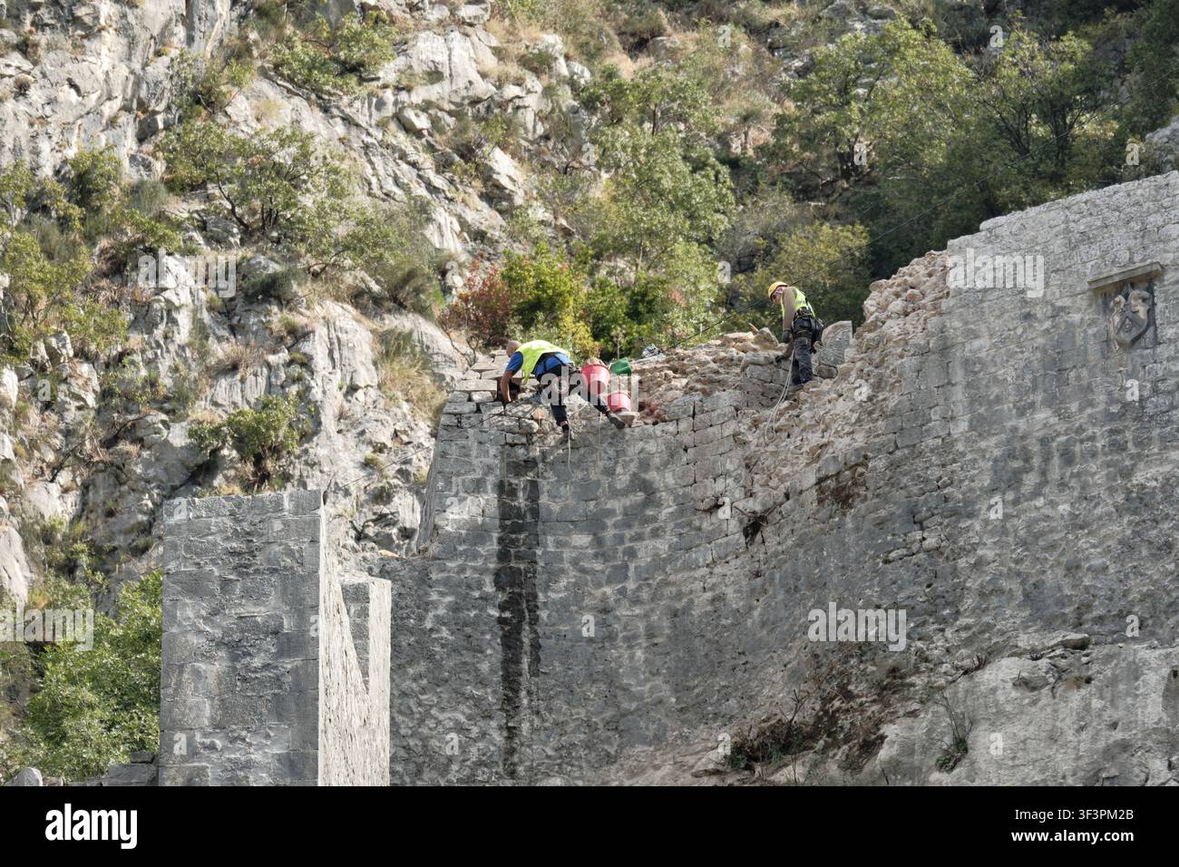 Ouvrier, suspendu à des cordes et attaché à un harnais, travaille pour la conservation du patrimoine culturel à Kotor, au Monténégro Banque D'Images