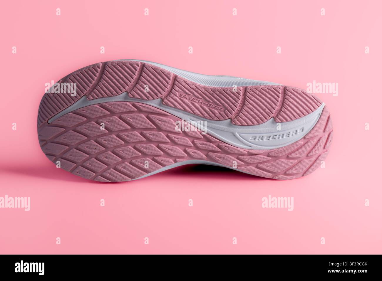 Lviv, Ukraine - 25 juillet 2026 : Vue inférieure de la semelle de baskets de course roses Skechers avec motif de rainure sur fond rose Banque D'Images