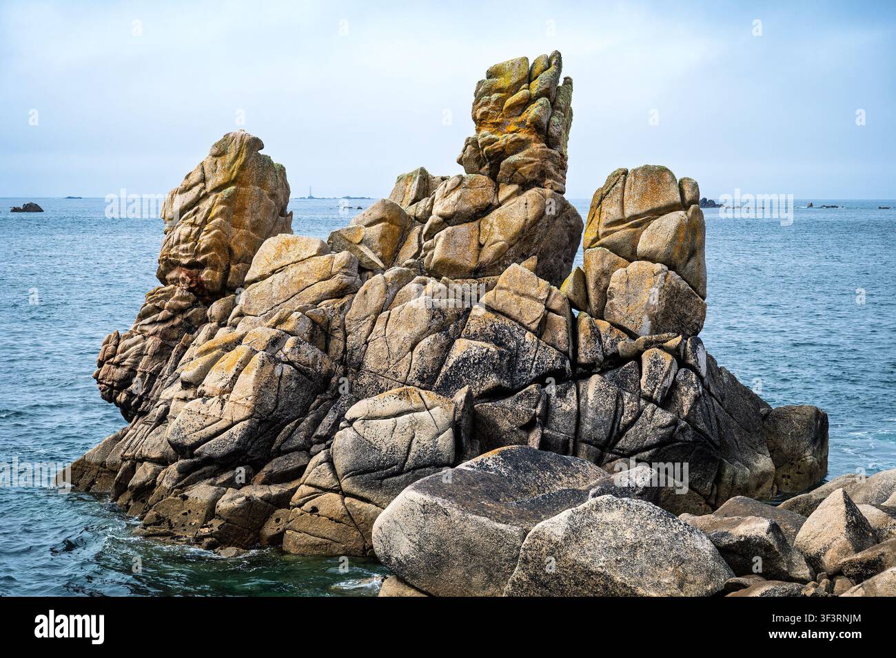 Formation rocheuse en forme de trident près de Long Point, St Agnes, îles Scilly, Royaume-Uni. Le phare de Bishop Rock est visible entre les piles. Banque D'Images