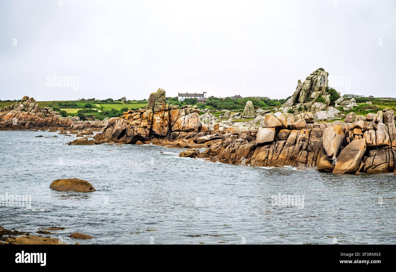 La côte rocheuse de Porth Warna, sur la côte ouest de St Agnes, îles Scilly, Royaume-Uni. Le bâtiment de l'ancien poste de garde-côte est visible. Banque D'Images