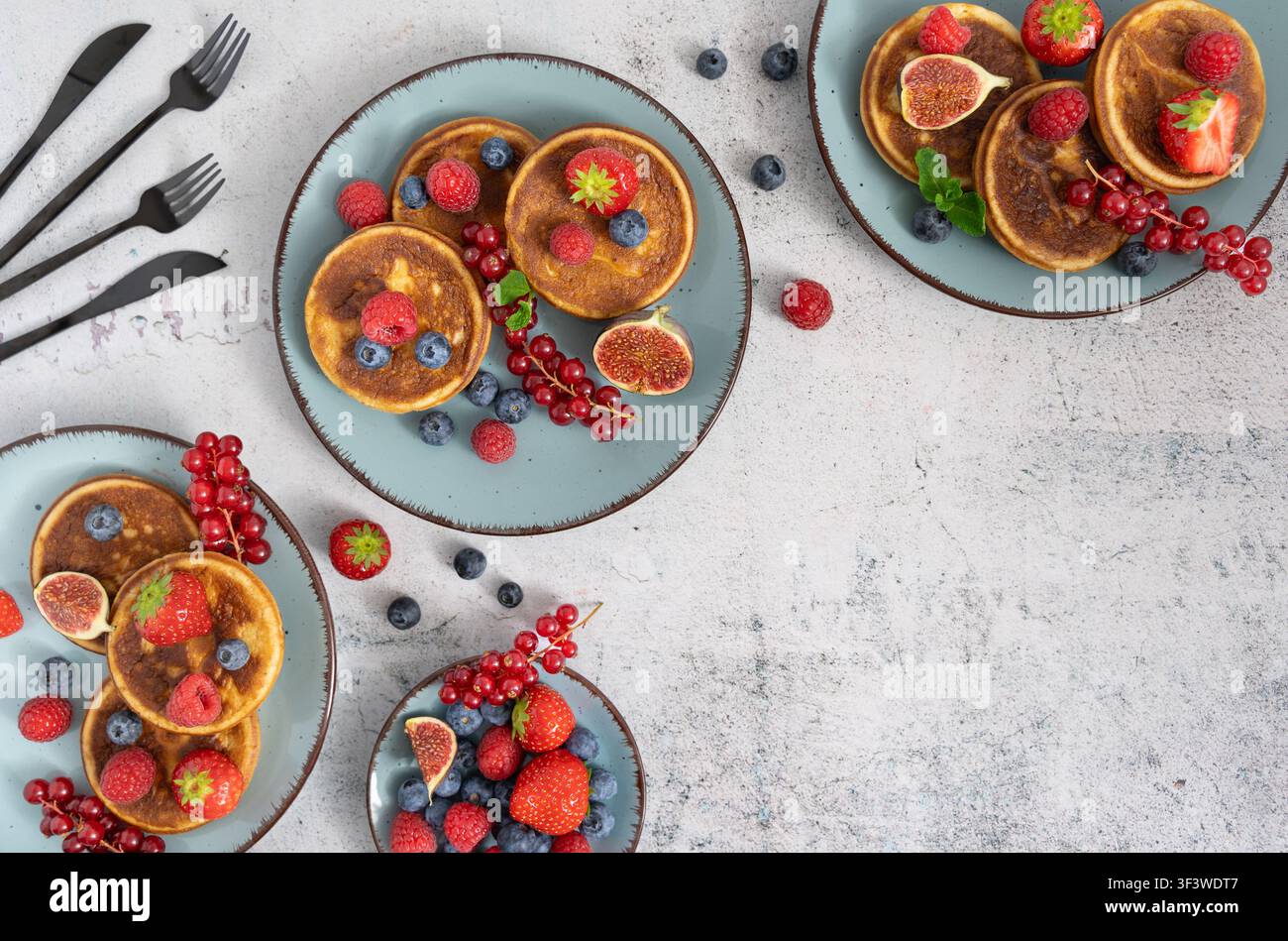 Composition de brunch en vue aérienne mettant en avant des pancakes garnis de fruits disposés sur un fond texturé Banque D'Images