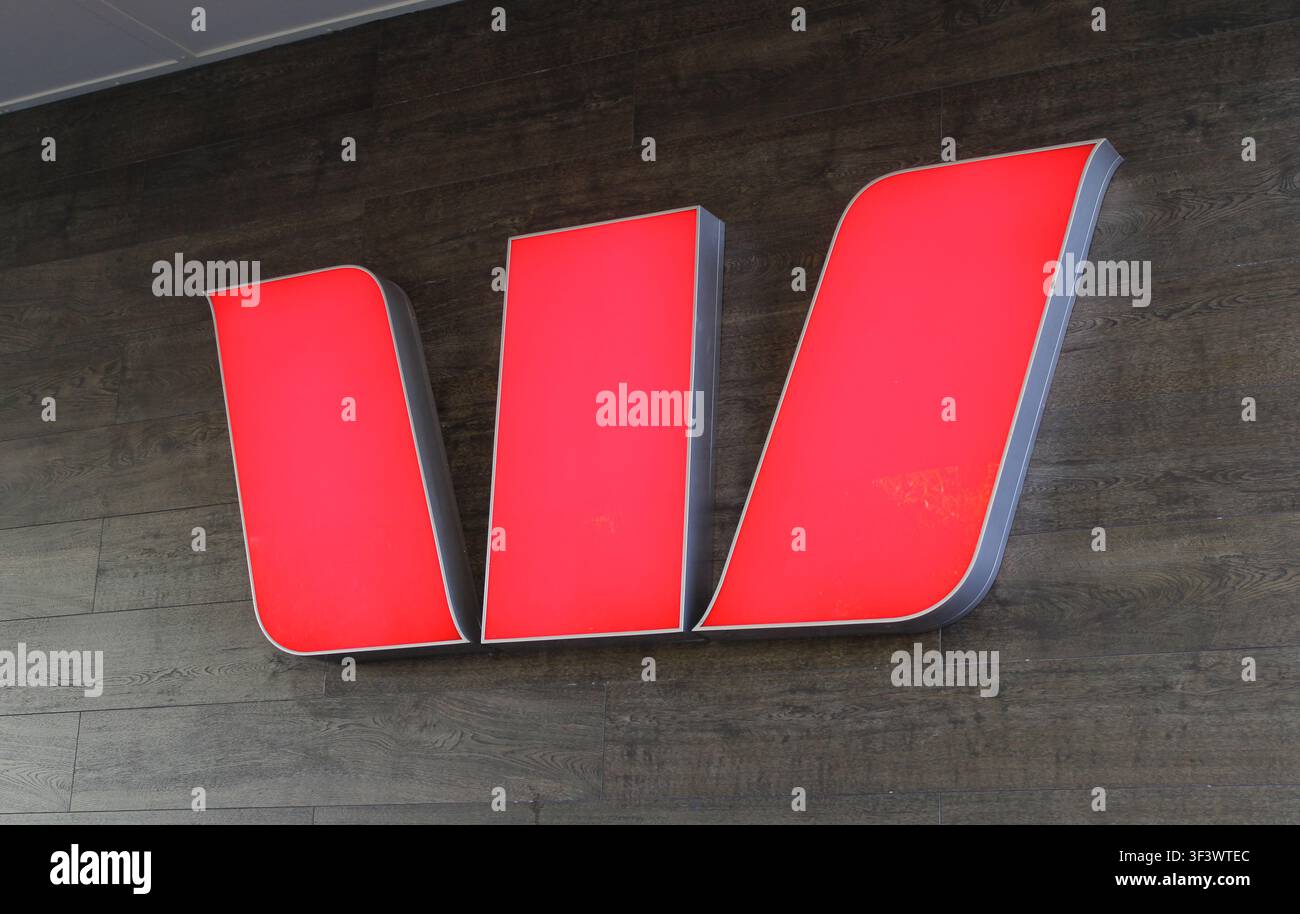 La signalisation distinctive rouge lumineuse du logo « W » de la banque Westpac montée sur un mur extérieur d'une succursale australienne Banque D'Images