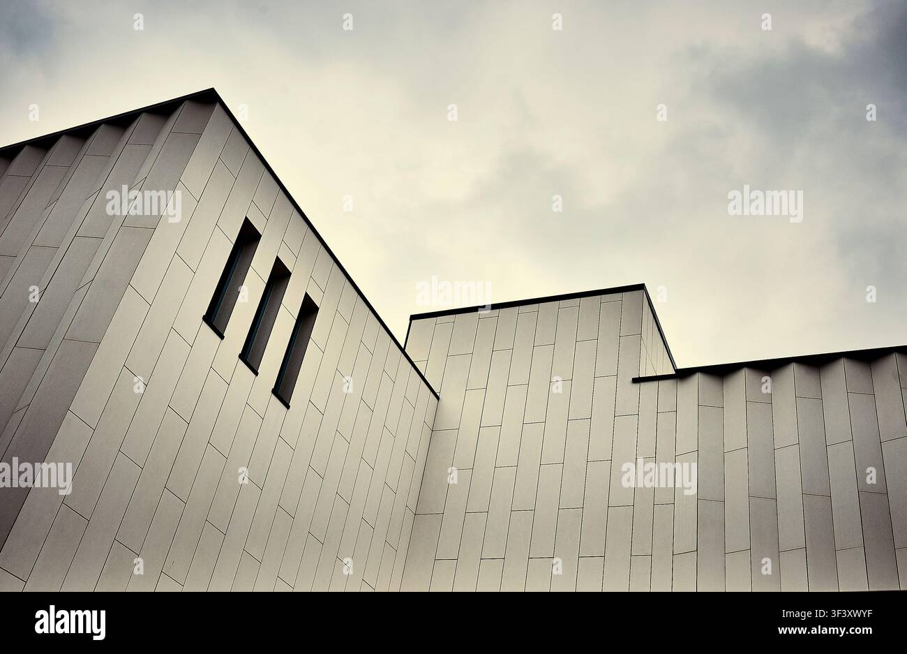 Bâtiment contemporain revêtu de panneaux métalliques avec trois fenêtres en forme de „fente de tir“, Royaume-Uni Banque D'Images