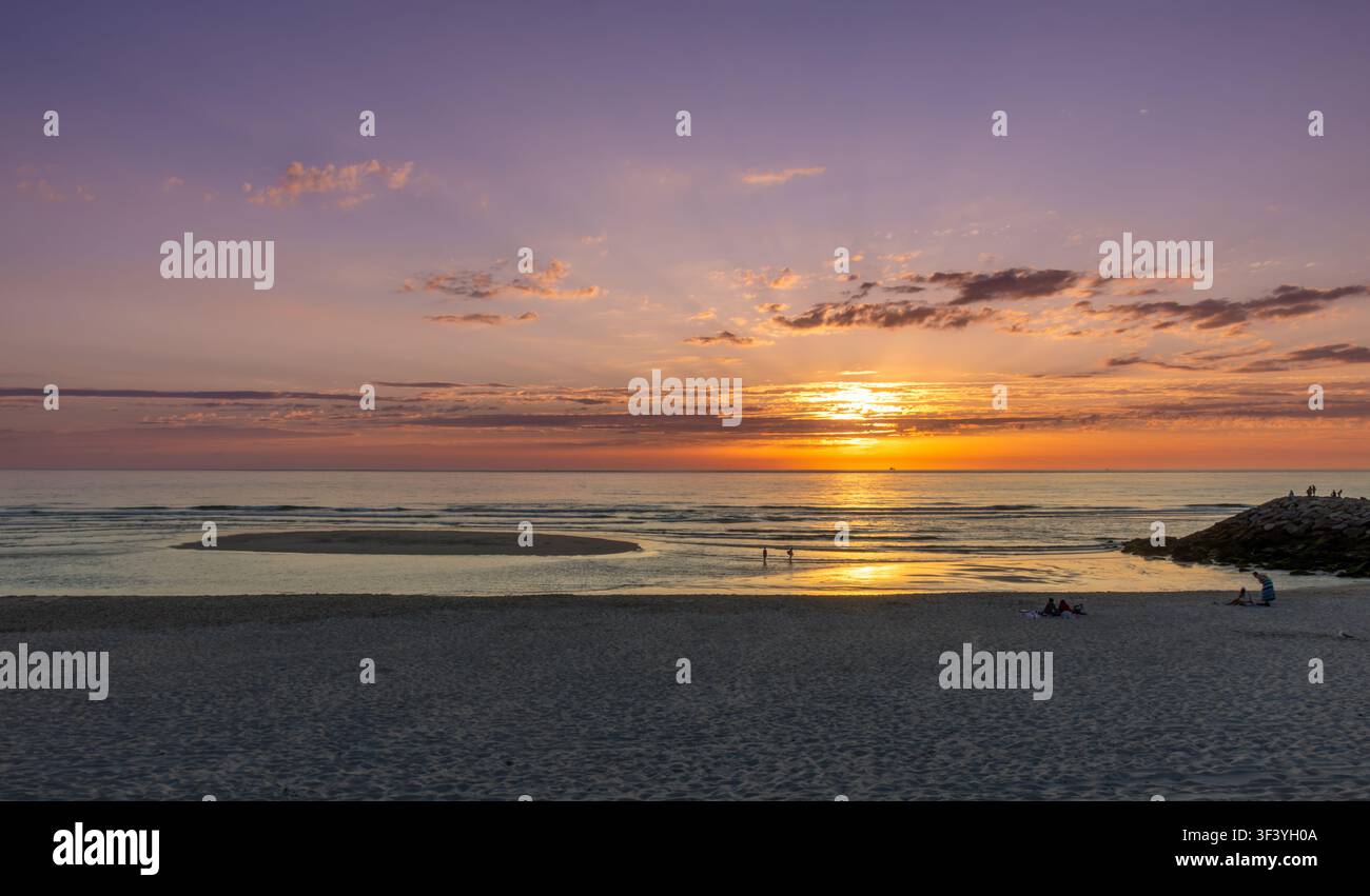 Couchant doré sur la plage de Costa Nova, près d'Aveiro, au Portugal. La lumière chaude du soleil se reflète dans le calme de l'océan Atlantique. Banque D'Images