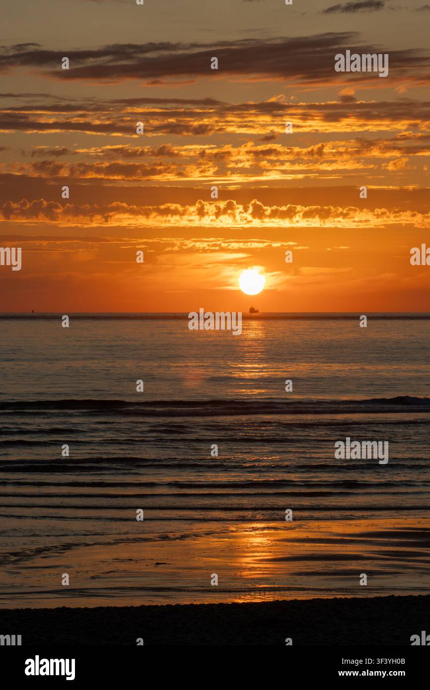 Couchant doré sur la plage de Costa Nova, près d'Aveiro, au Portugal. La lumière chaude du soleil se reflète dans le calme de l'océan Atlantique. Banque D'Images