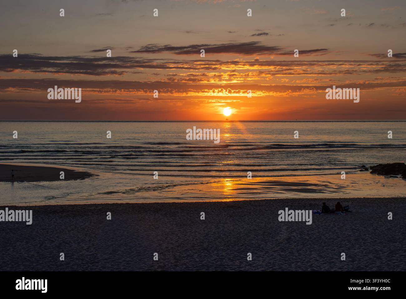Couchant doré sur la plage de Costa Nova, près d'Aveiro, au Portugal. La lumière chaude du soleil se reflète dans le calme de l'océan Atlantique. Banque D'Images