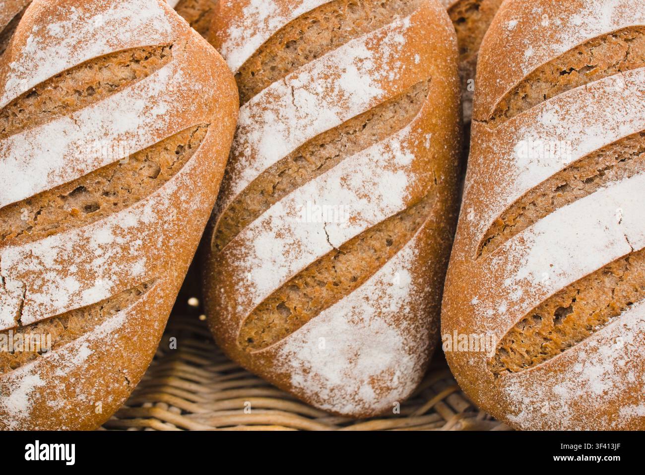 Pain de seigle artisanal fraîchement cuit présenté dans un panier en osier sur un marché à Arles, France. Banque D'Images
