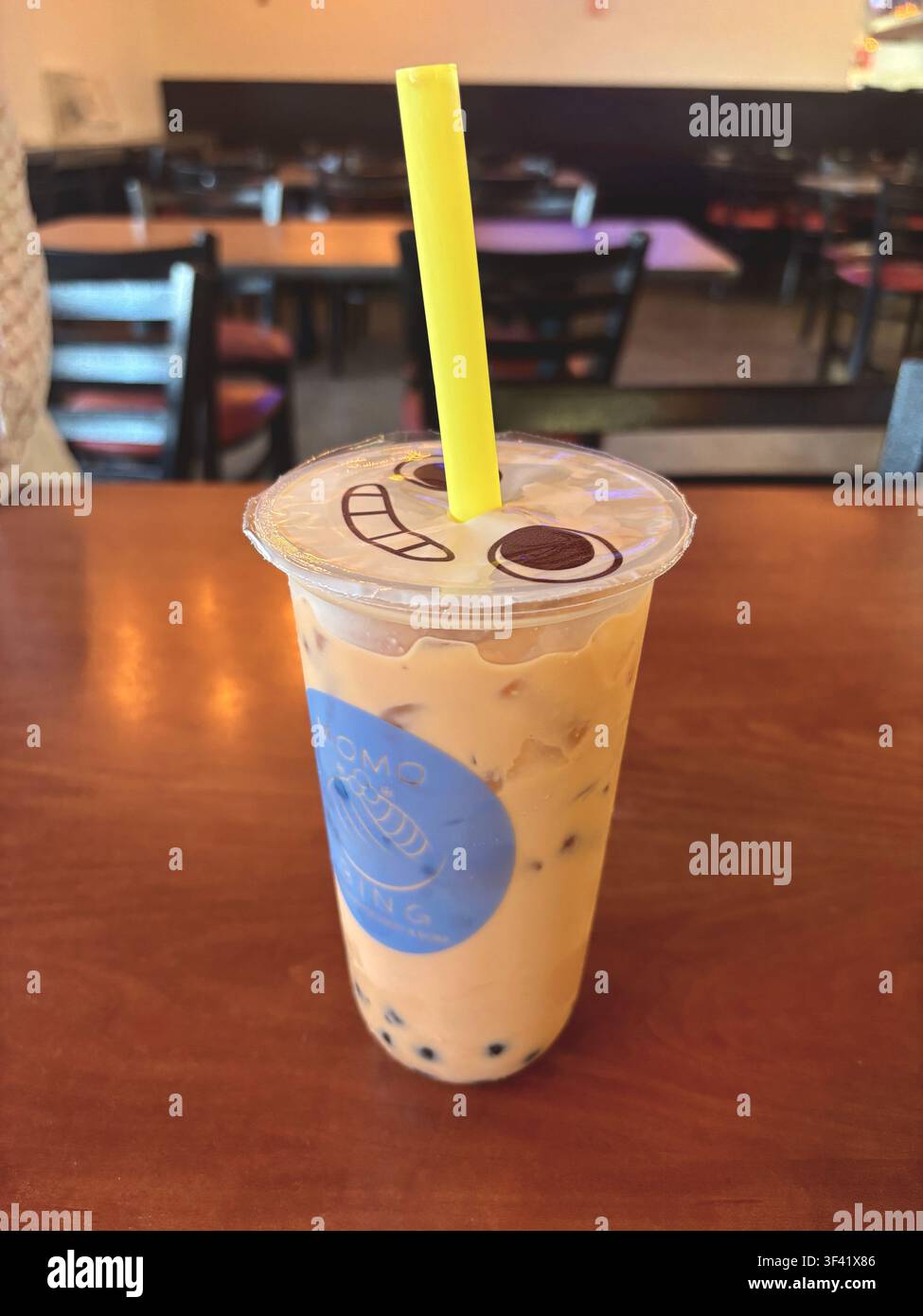 Thé au lait glacé Boba avec perles de tapioca et motif de couvercle de dessin animé sur une table en bois Banque D'Images
