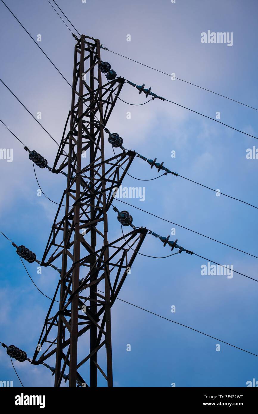 Tour de transmission en treillis d'acier soutenant des lignes électriques à haute tension contre un ciel bleu Banque D'Images