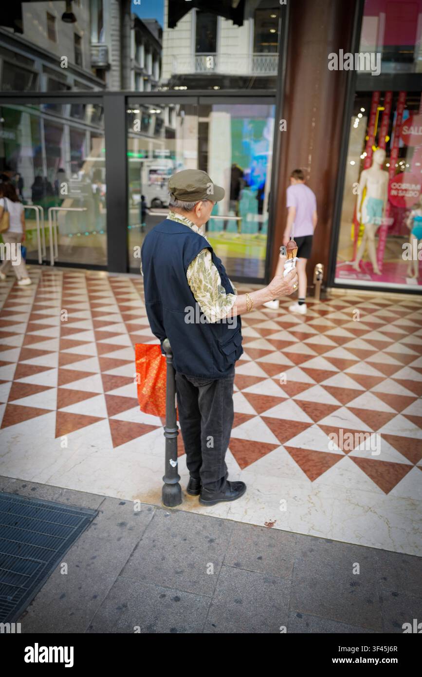Un homme plus âgé se tient dans la rue avec une glace à la main. *** Un homme plus âgé se tient dans la rue avec une glace en main  RECORD Banque D'Images