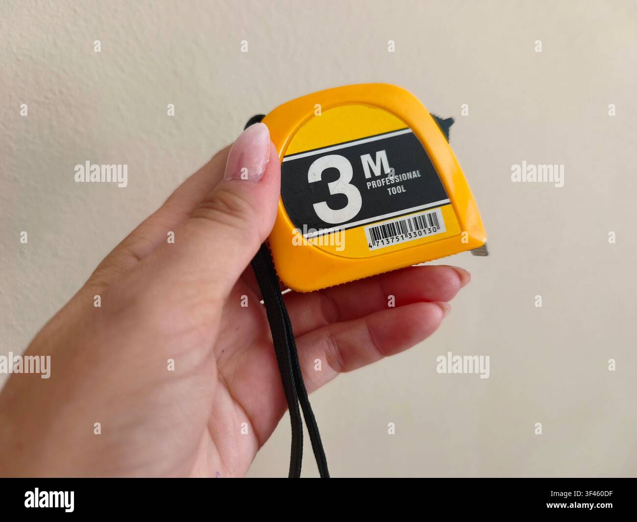 Femme tenant à la main un mètre-ruban professionnel jaune de trois mètres - Image de stock capturée avec un smartphone