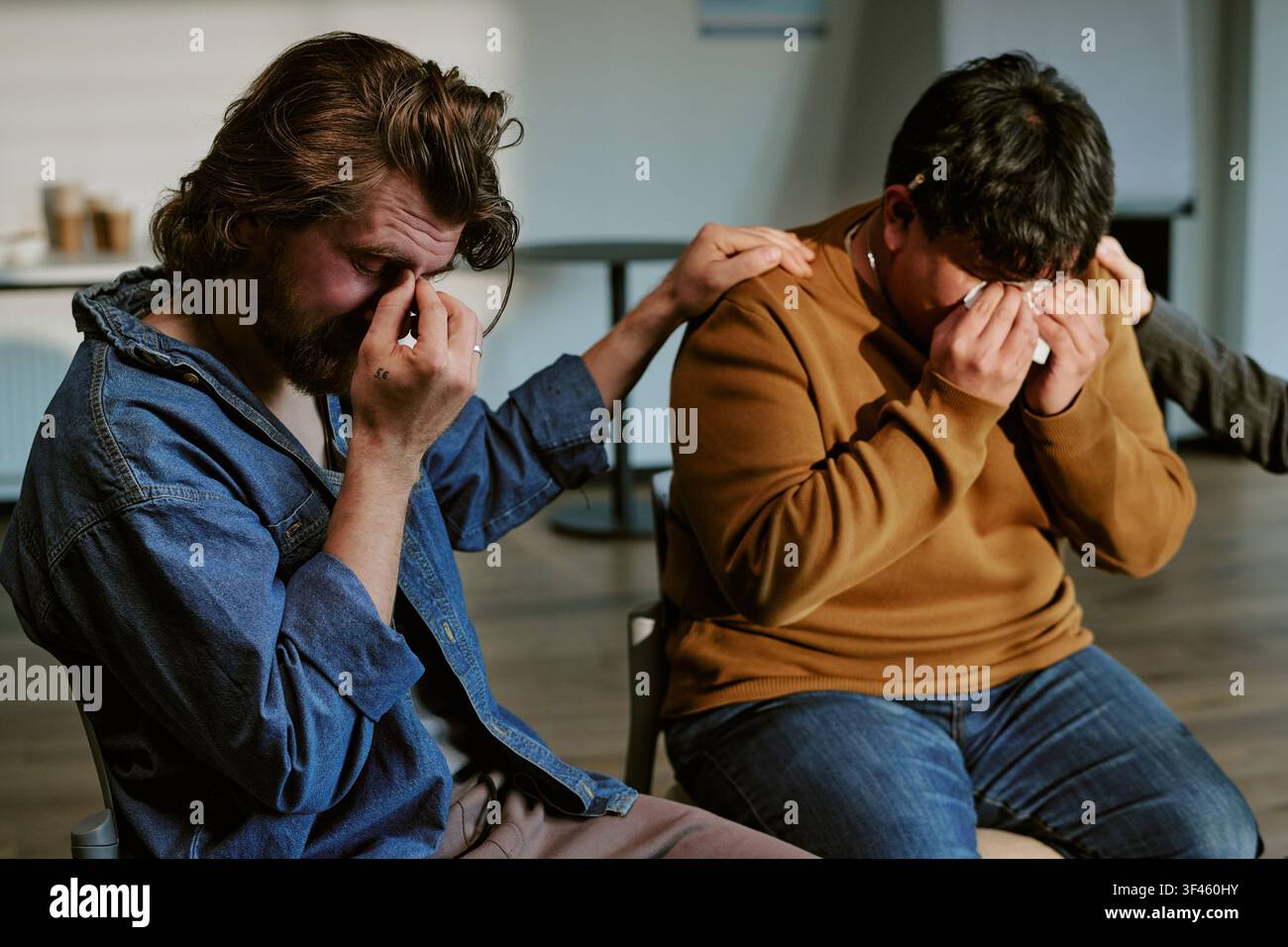 Hommes adultes pleurant lors d'une séance de thérapie de groupe de soutien Banque D'Images