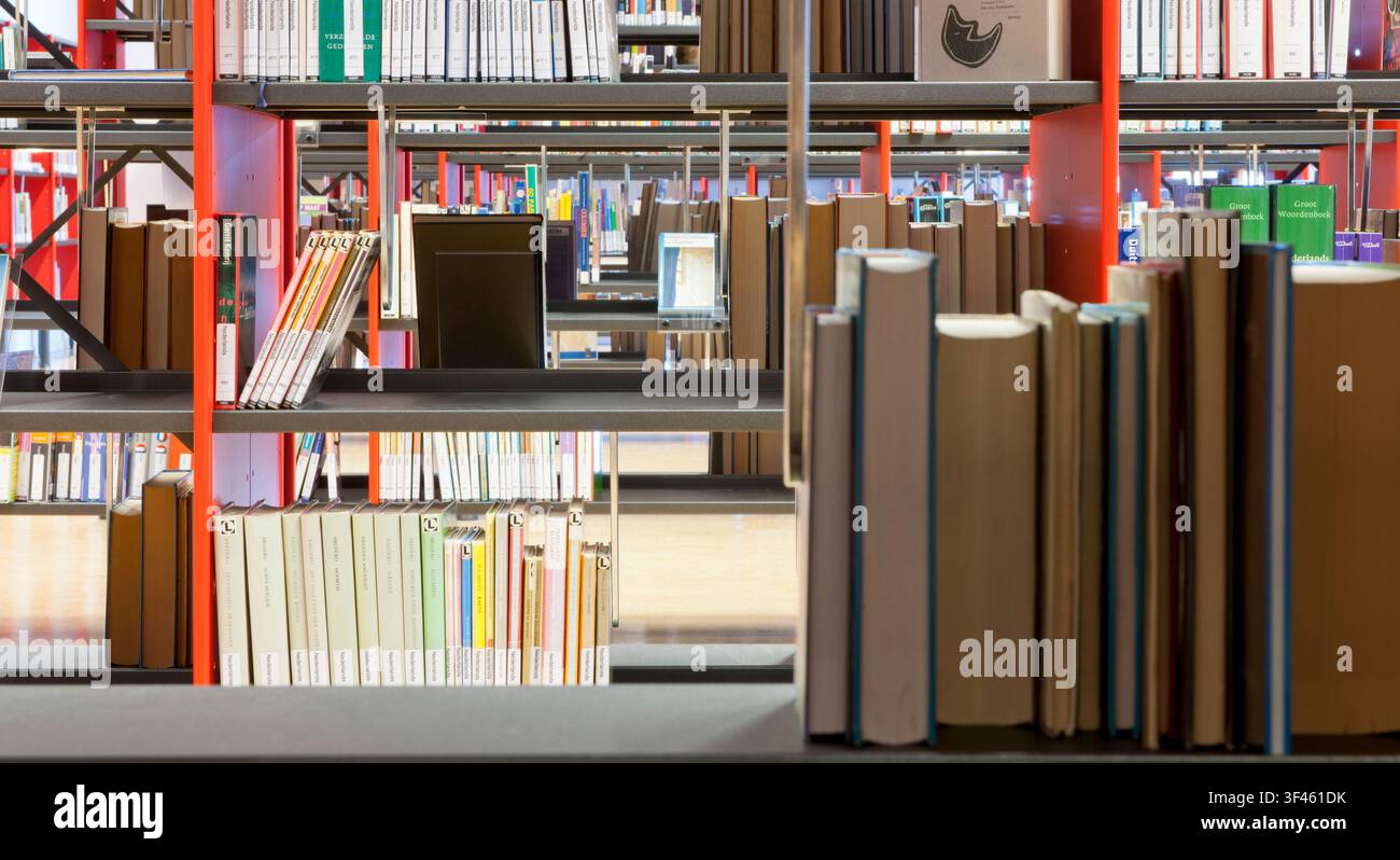 Livres sur une étagère dans une bibliothèque publique, avec des espaces vides sur les étagères. Banque D'Images