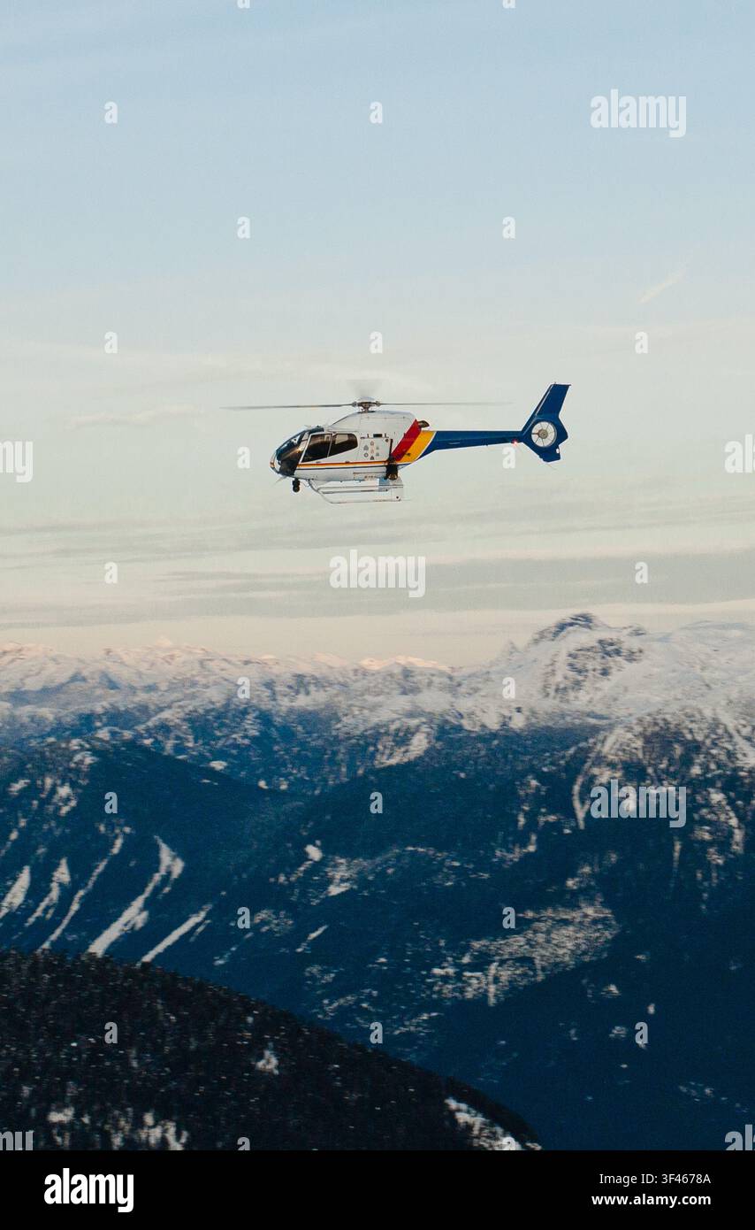 Hélicoptère de police patrouillant au-dessus d'une chaîne de montagnes enneigée Banque D'Images