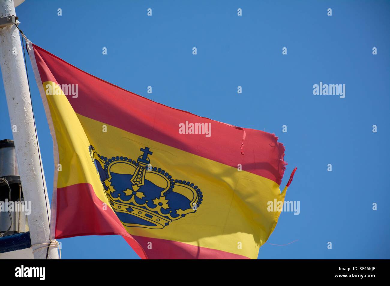 Un drapeau civil espagnol en tant que drapeau de plaisance, drapeau espagnol avec la couronne royale flottant sur un mât blanc contre un ciel bleu clair. Banque D'Images