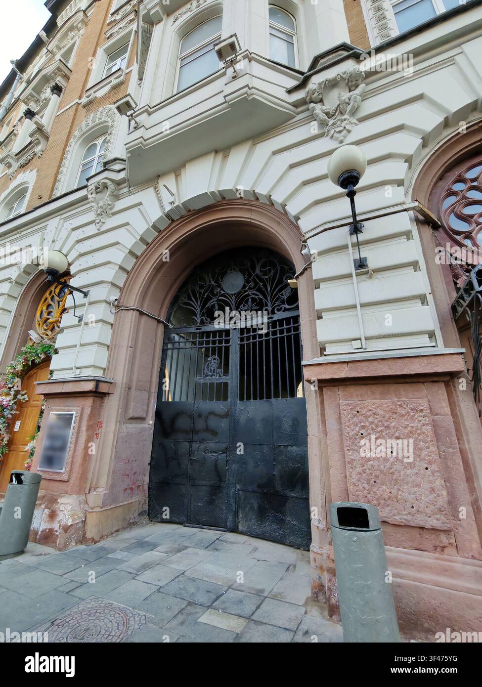 Une grande porte en fer forgé sous une arche en pierre ornée de sculptures détaillées et de colonnes. Cette image capture des thèmes de l'histoire urbaine et Banque D'Images