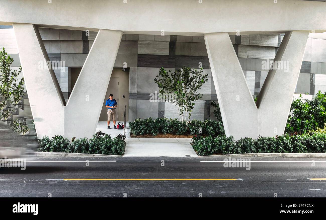Un homme debout près de l'entrée d'un immeuble Banque D'Images