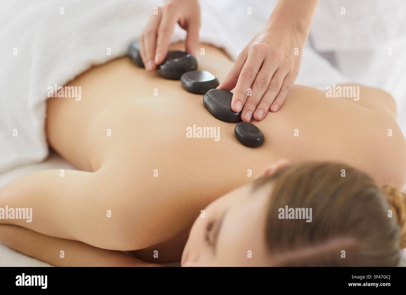 Jeune femme détendue profitant d'un massage aux pierres dans un salon de beauté, traitement corporel dans un centre de bien-être Banque D'Images