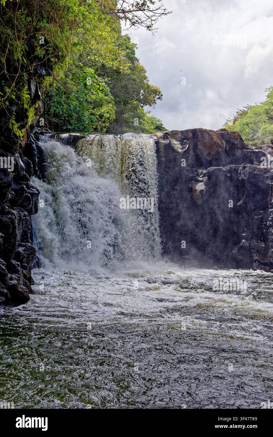 Un plan vertical et moyen capturant la force naturelle de la cascade de Grand River South East (GRSE) à Maurice. L'eau dévale lourdement sur un jag Banque D'Images