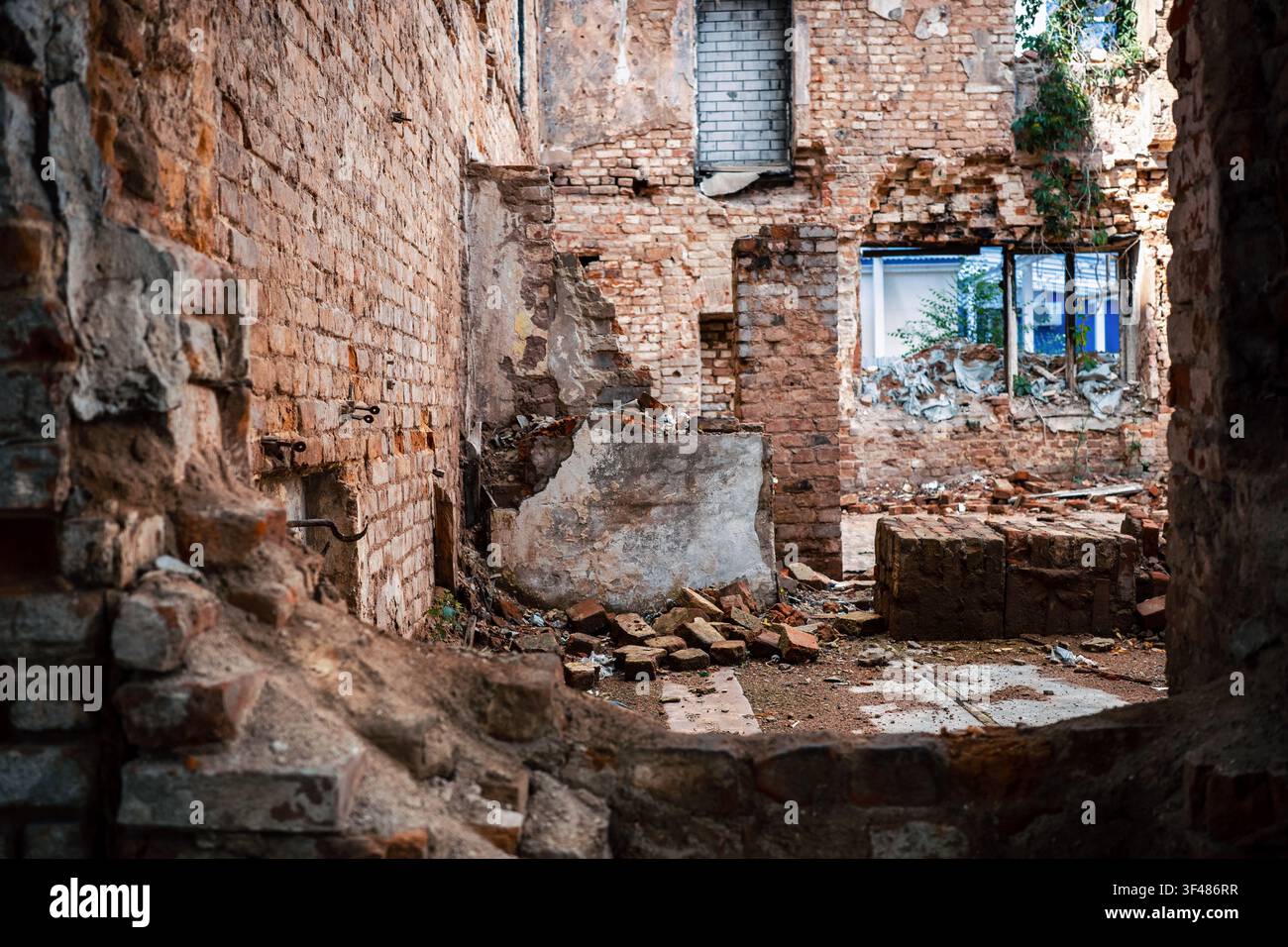 Intérieur d'un bâtiment en briques abandonné avec gravats et murs exposés, architecture en ruine pour démolition, rénovation, récupération après désastre, dommages aux logements et délabrement urbain. Banque D'Images