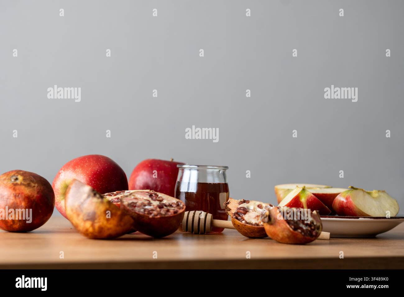 Nature morte pour la fête de Rosh Hashanah avec des pommes tranchées, un pot de miel et un cuillère, et un grenade sur une table en bois, symbolisant une douce Nouvelle Année juive Banque D'Images