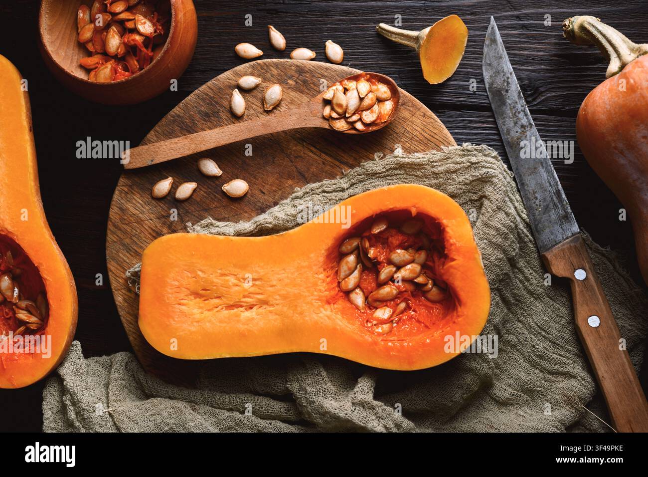 Vue de dessus de courge butternut crue avec cuillère en bois et graines sur planche à découper en bois. Des moitiés de citrouille se rapprochent. Photographie culinaire Banque D'Images