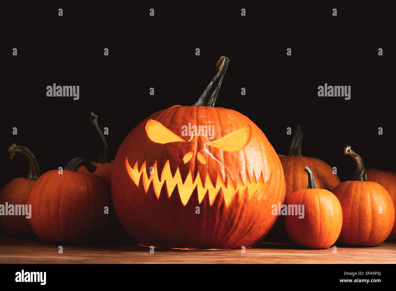 Lanterne de citrouille sculptée et lumineuse entourée de citrouilles créant une décoration festive pour Halloween. La lumière chaude des bougies et les ombres dramatiques renforcent l'atmosphère effrayante des fêtes Banque D'Images