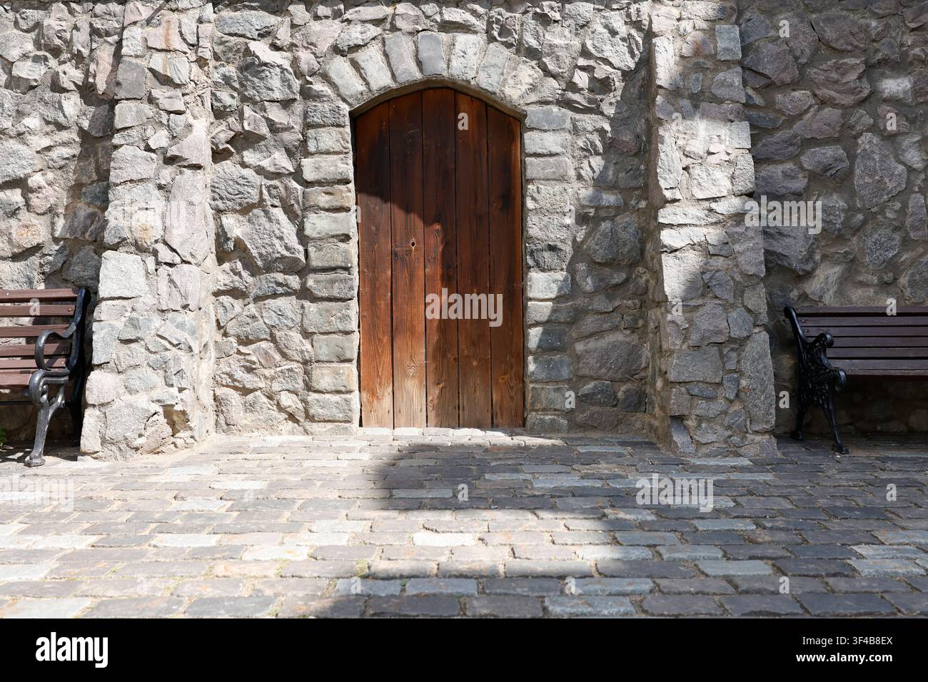 Mur de pierre ancien porte en bois arquée tendance cottagecore. Façade de château de vieille ville européenne restaurée avec balustrade en fer forgé et vintage Banque D'Images