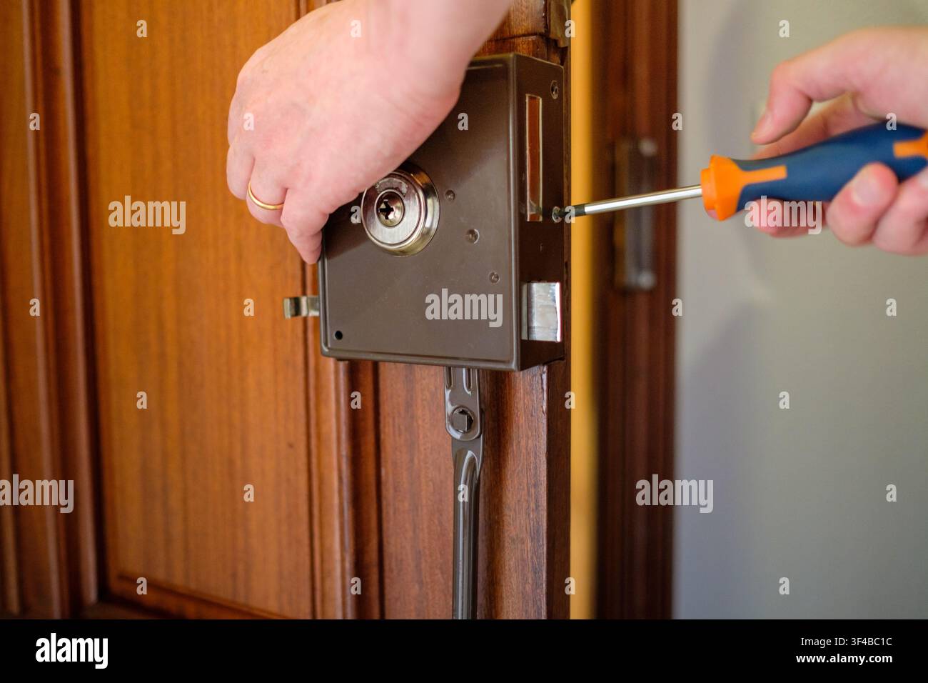 Mains de serrurier installant une nouvelle serrure de sécurité sur une porte en bois Banque D'Images