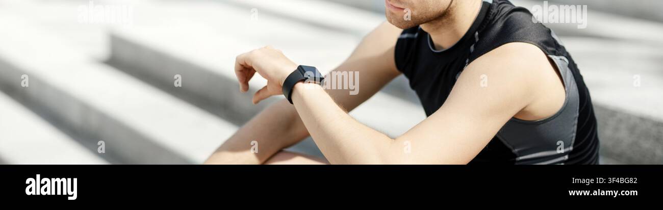 Vérification des rythmes biologiques du corps. Guy dans les vêtements de sport regardant le tracker de forme physique sur le bras, assis sur les marches Banque D'Images
