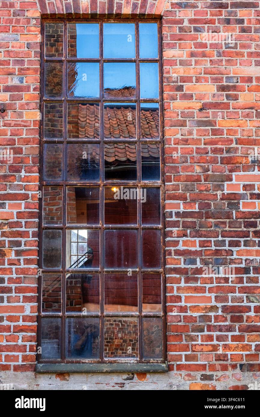 Ancienne belle fenêtre sur un bâtiment industriel en briques Banque D'Images