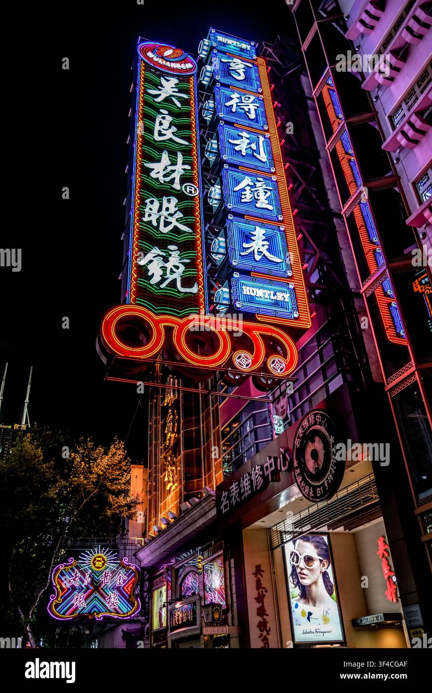 Une prise verticale capture une haute façade de bâtiment ornée de multiples enseignes au néon lumineuses en rouge, vert, bleu et blanc avec des caractères chinois, contre Banque D'Images