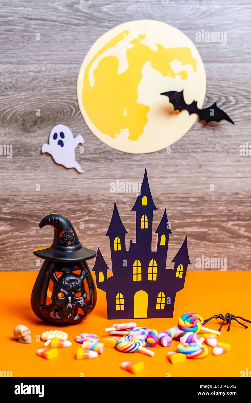 Décoration Halloween avec maison hantée, pleine lune, fantôme, chauve-souris et sucreries sur fond orange Banque D'Images