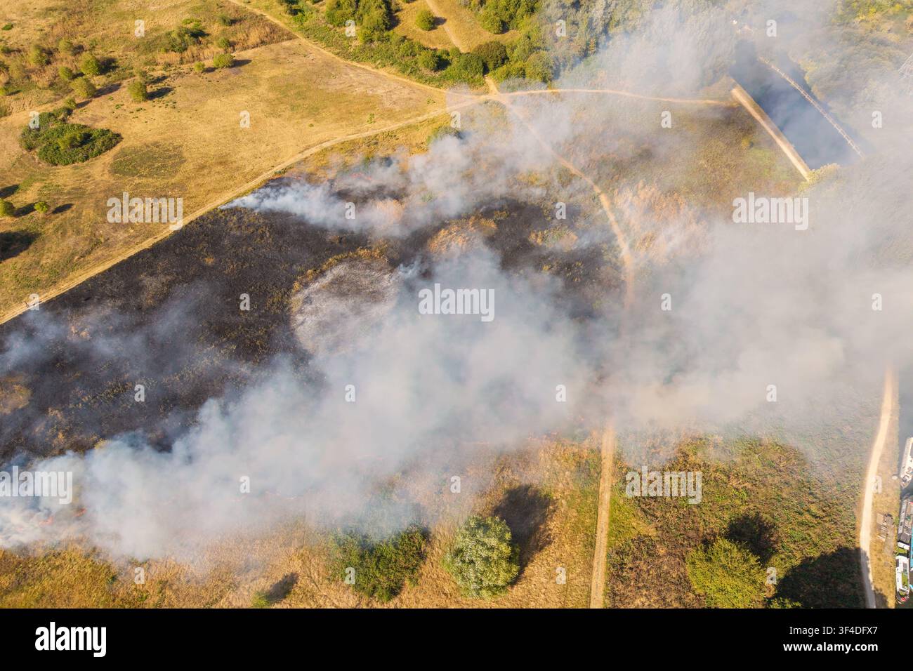 Une photo aérienne dramatique capturant un feu de forêt à Rammey Marsh dans le nord de Londres, avec une épaisse fumée qui s'élève et des flammes vives brûlant à travers les prairies sèches. Banque D'Images
