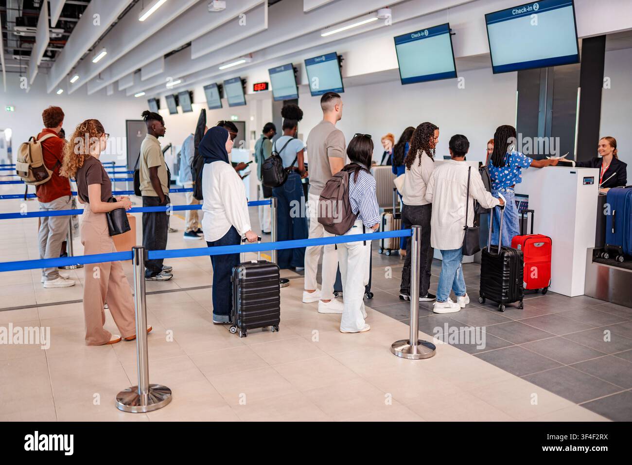 Passagers attendant en file au comptoir d'enregistrement de l'aéroport avec leurs bagages Banque D'Images