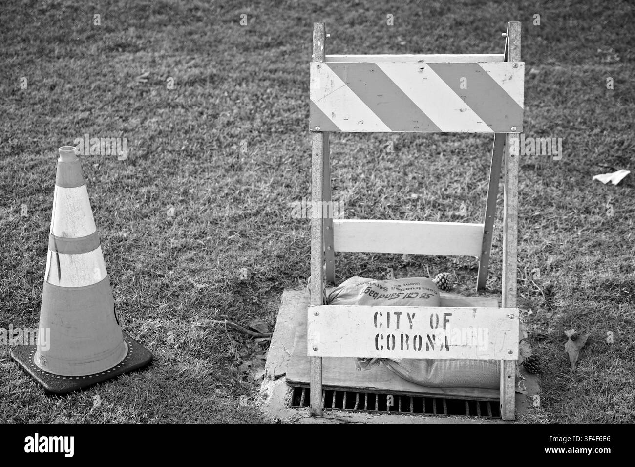 Barrière de chantier temporaire et cône de signalisation placé sur un drain d'orage à Ridgeview Park, avec un panneau étiqueté Ville de Corona indiquant la municipalité Banque D'Images
