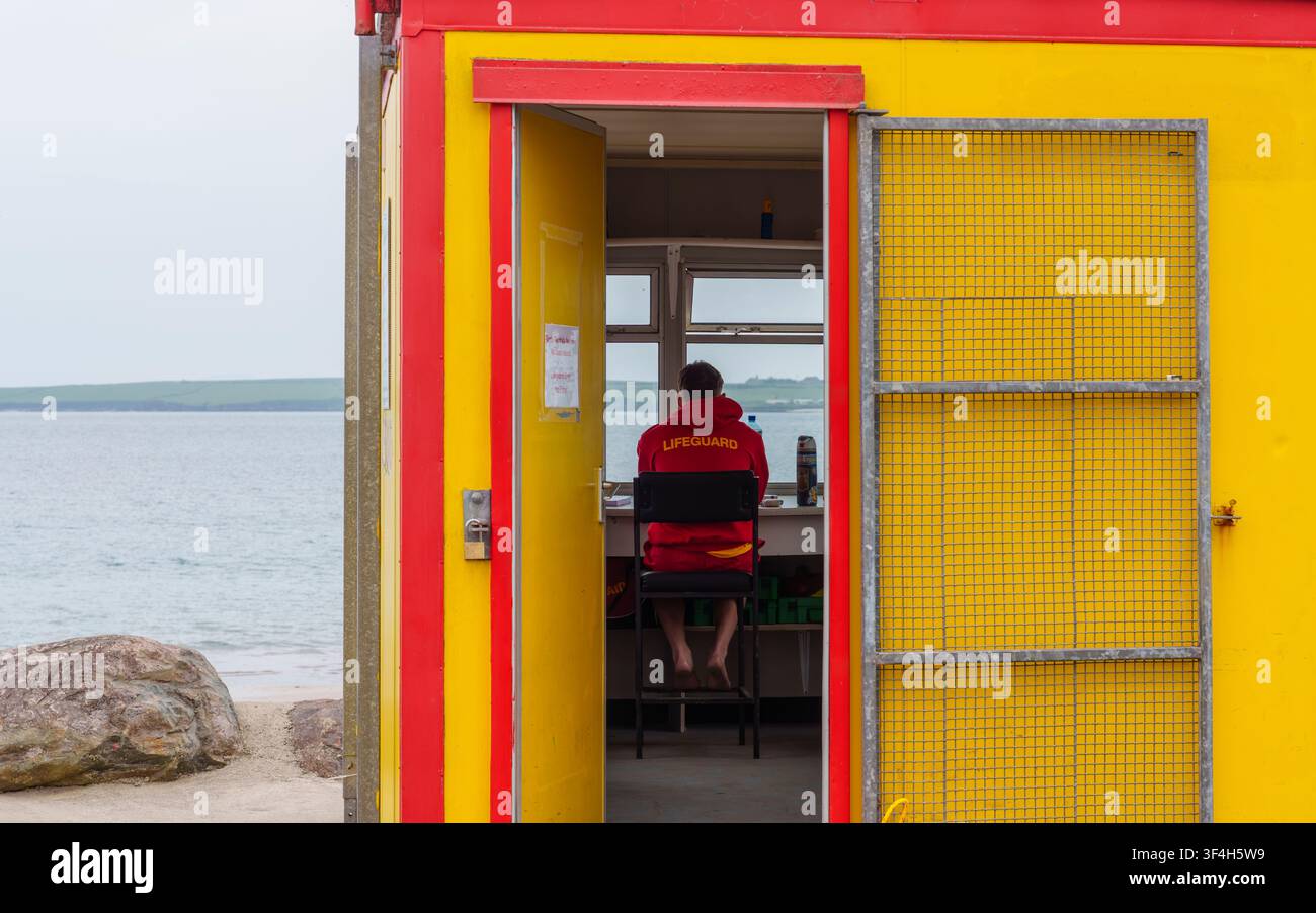 Maître-nageur en service dans une station jaune vif surplombant la plage de Fionntrá (Ventry) et le port de Ventry sur la péninsule de Dingle, comté de Kerry, Irlande. Banque D'Images
