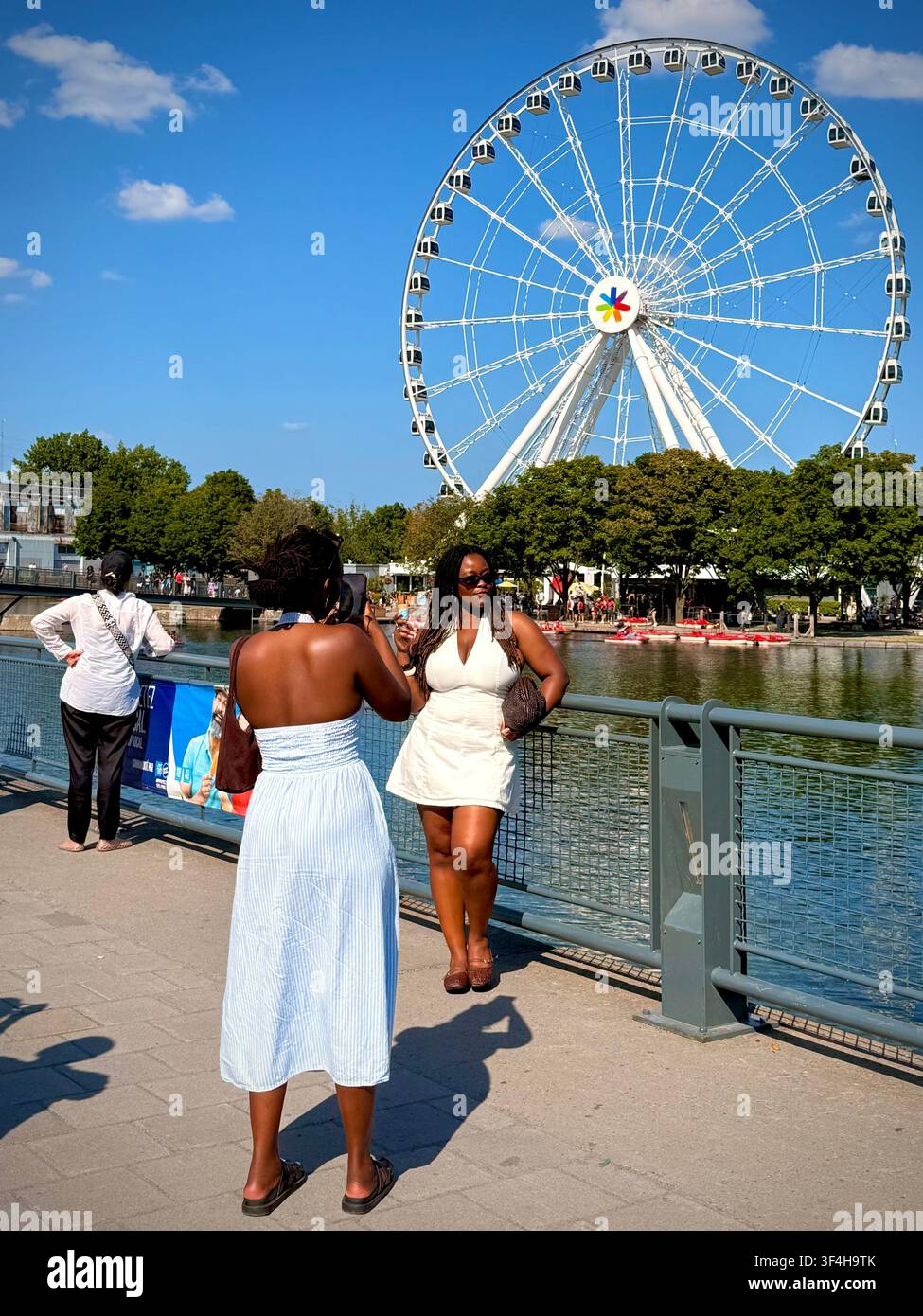 Les visiteurs prennent des photos sur le front de mer du Vieux-Port avec la grande roue de Montréal, La Grande Roue de Montréal, en arrière-plan, Montréal, Québec, Canada. Banque D'Images