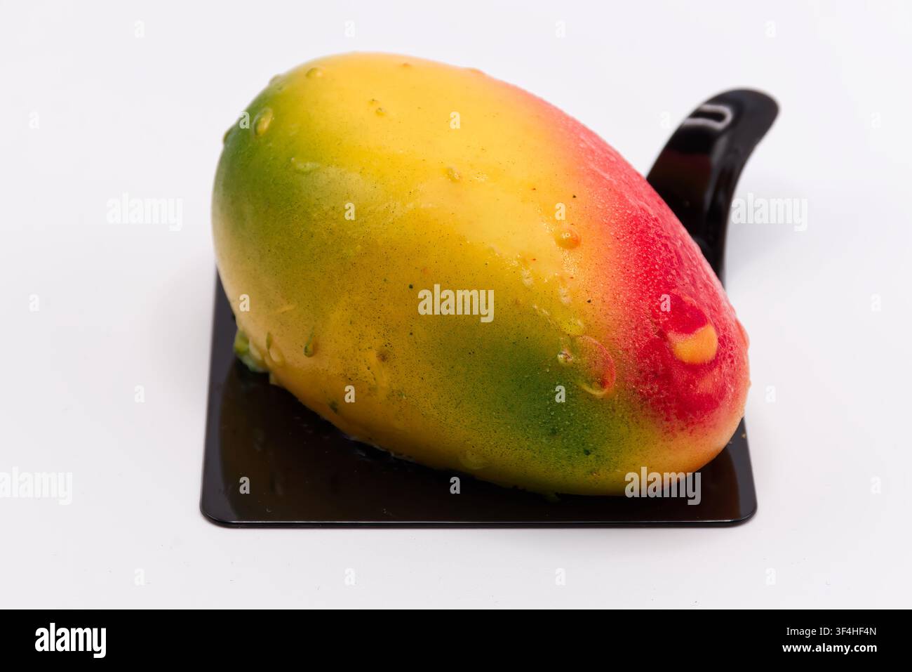 Dessert réaliste en forme de mangue, pâtisserie trompe-l'œil servie sur fond blanc. Banque D'Images